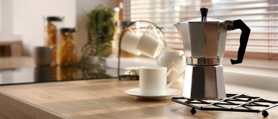 Grid with geyser coffee maker and cup on kitchen counter near window
