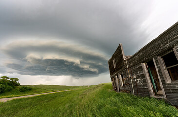 Supercell storm forming over abandoned wooden building and prairie field