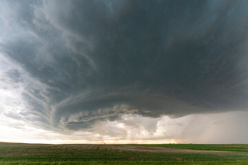 Supercell storm clouds gathering over green fields
