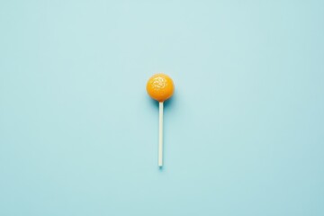 A single orange lollipop on a light blue background