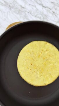 Sauteing a hot corn tortilla on frying pan
