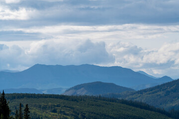 Fototapeta premium Breathtaking mountain range covered by forest under cloudy sky