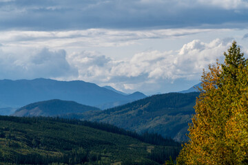 Fototapeta premium Rolling hills and distant peaks under cloudy sky in british columbia