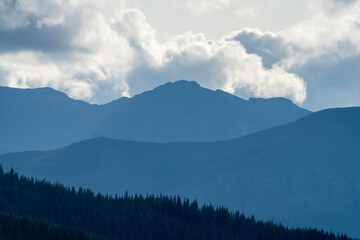 Naklejka premium Majestic mountain peaks loom over a serene forest landscape