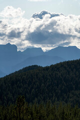Majestic mountains rising above evergreen forest under cloudy sky
