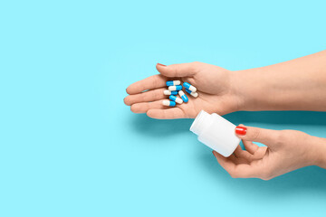 Female hands and bottle with pills on blue background