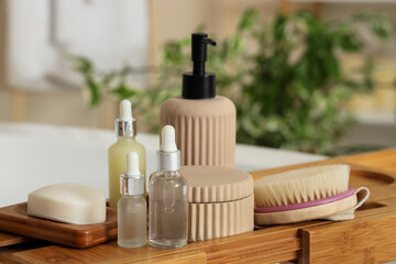 Different cosmetic products on wooden bathtub tray
