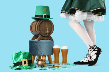 Woman in waitress costume with glasses of beer, barrel and leprechaun's hats on blue background....