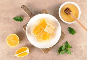 Acacia honey, honeycomb, lemon and mint leaves on beige background, copy space. Top view. 