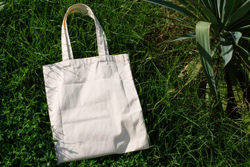 White cotton or mesh bag on green grass background. Zero waste, no plastic, eco friendly shopping,...