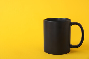 One blank black mug on yellow background. Mockup for design