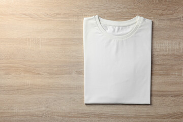Fototapeta premium One blank t-shirt on wooden background, top view. Mockup for design