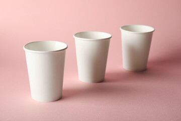 Paper cups on pink background, closeup. Mockup for design