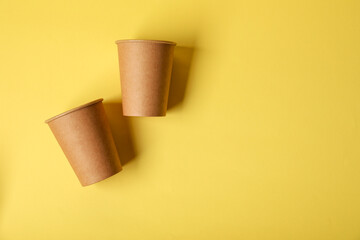 Paper cups on yellow background, flat lay. Mockup for design