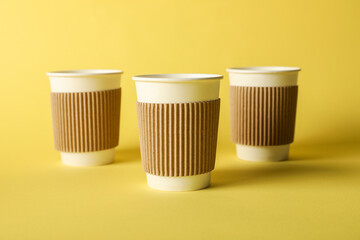 Paper cups on yellow background, selective focus. Mockup for design