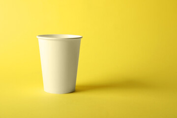 One paper cup on yellow background. Mockup for design