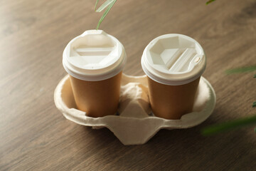 Holder with paper cups on wooden table, closeup. Mockup for design