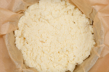 A top-down shot of a baking mold lined with parchment paper containing unbaked batter made from beaten egg whites and coconut