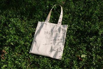 White cotton or mesh bag on green branches of a coniferous bush background. Zero waste, no plastic,...