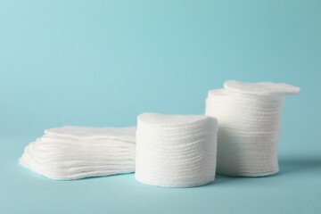 Clean cotton pads on light blue background, closeup. Space for text