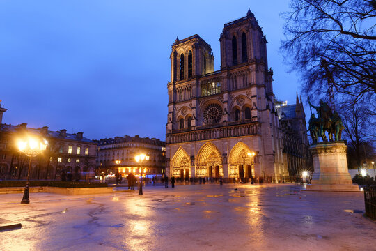 Beautiful cityscape view of the Notre-Dame Cathedral in Paris, France, on a rainy spring evening with reflection in the blue hour - Powered by Adobe