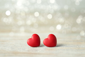 Fototapeta premium Valentine's day greeting card. Small red hearts on table, bokeh effect. Space for text