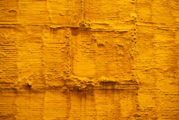 Bright yellow textured wall creates a vibrant backdrop in an urban setting during daylight hours