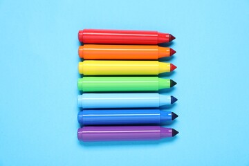 Fototapeta premium Many colorful markers on light blue background, flat lay