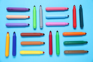 Many colorful markers on light blue background, flat lay