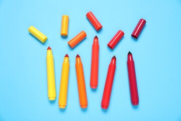 Many colorful markers on light blue background, flat lay