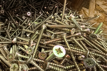 Collection of shiny screws stacked high in a workshop environment