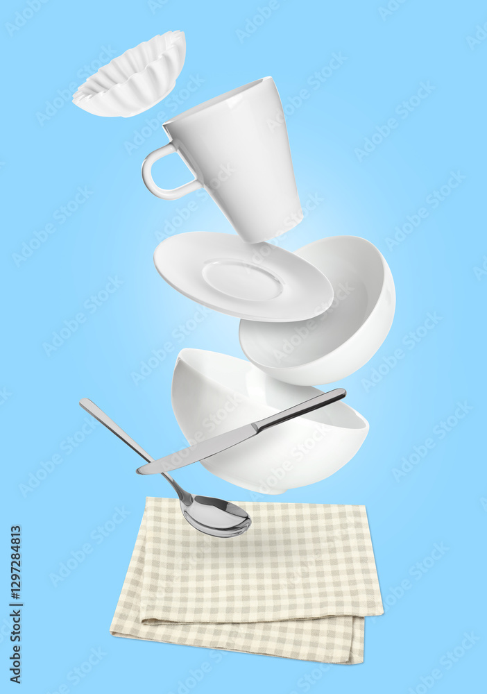 Wall mural Clean dishware and silverware flying over checkered napkin on light blue background