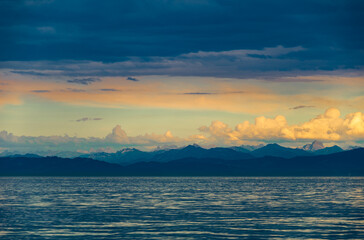 Majestic sunset over tranquil ocean and distant mountain range creates a stunning color palette