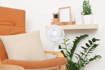 Electric fan and houseplants on armchair at home
