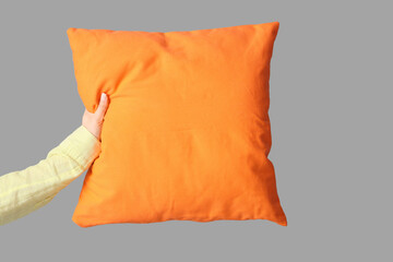 Woman with bright orange pillow on grey background