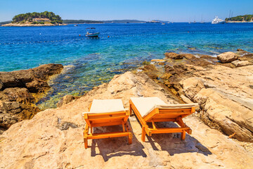 Coastal summer landscape - view of the beach loungers on a rocky seashore, on the island of Hvar, the Adriatic coast of Croatia
