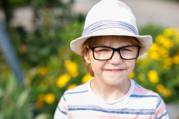 A young blonde boy with large glasses and a straw sunhat is featured in a portrait