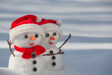 View of a couple of snowmen in a santa hats on their heads in a winter forest. Holiday christmas...