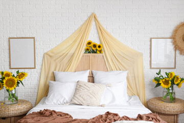Interior of light bedroom with cozy bed and beautiful sunflowers
