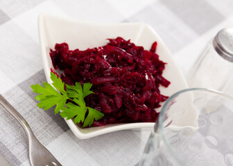 Traditional salad of Russian cuisine from boiled grated beetroot, decorated with a sprig of parsley