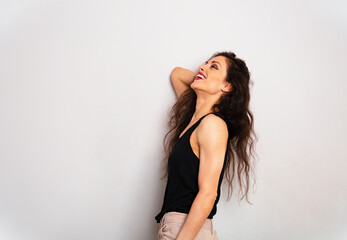 Happy enjoying laughing make-up woman with red lipstick looking up standing in black summer top on blue studio empty copy space background. Expression fun positive portrait