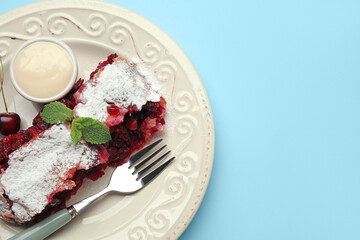 Plate with piece of tasty cherry strudel and sauce on blue background, closeup