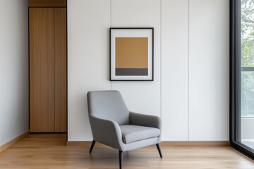 Modern minimalist interior with a cozy gray armchair, abstract framed artwork, natural wood accents, and large window providing bright natural light