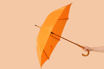 Female hand with umbrella on beige background