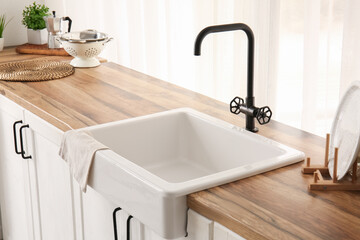 Sink on wooden counter near window in beautiful kitchen