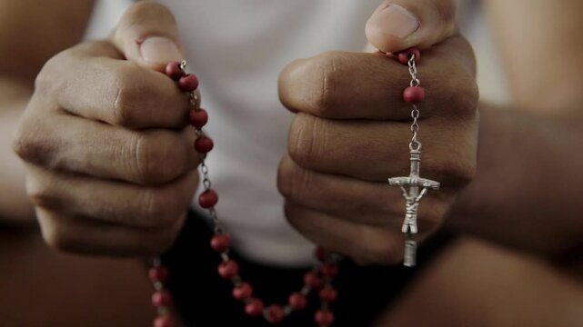 Praying hands holding rosary beads and crucifix