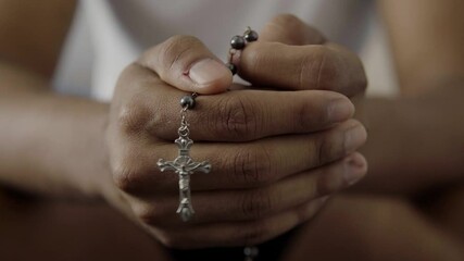 Hands holding rosary beads while praying - Powered by Adobe
