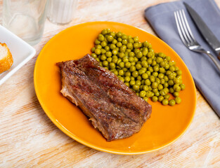 Delicious tender grilled veal tenderloin served for dinner with garnish of canned green pea..