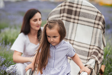 Mother and little daughter in a flowering lavender field enjoying her scent.