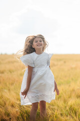 Child girl running through field of wheat, sunset.
